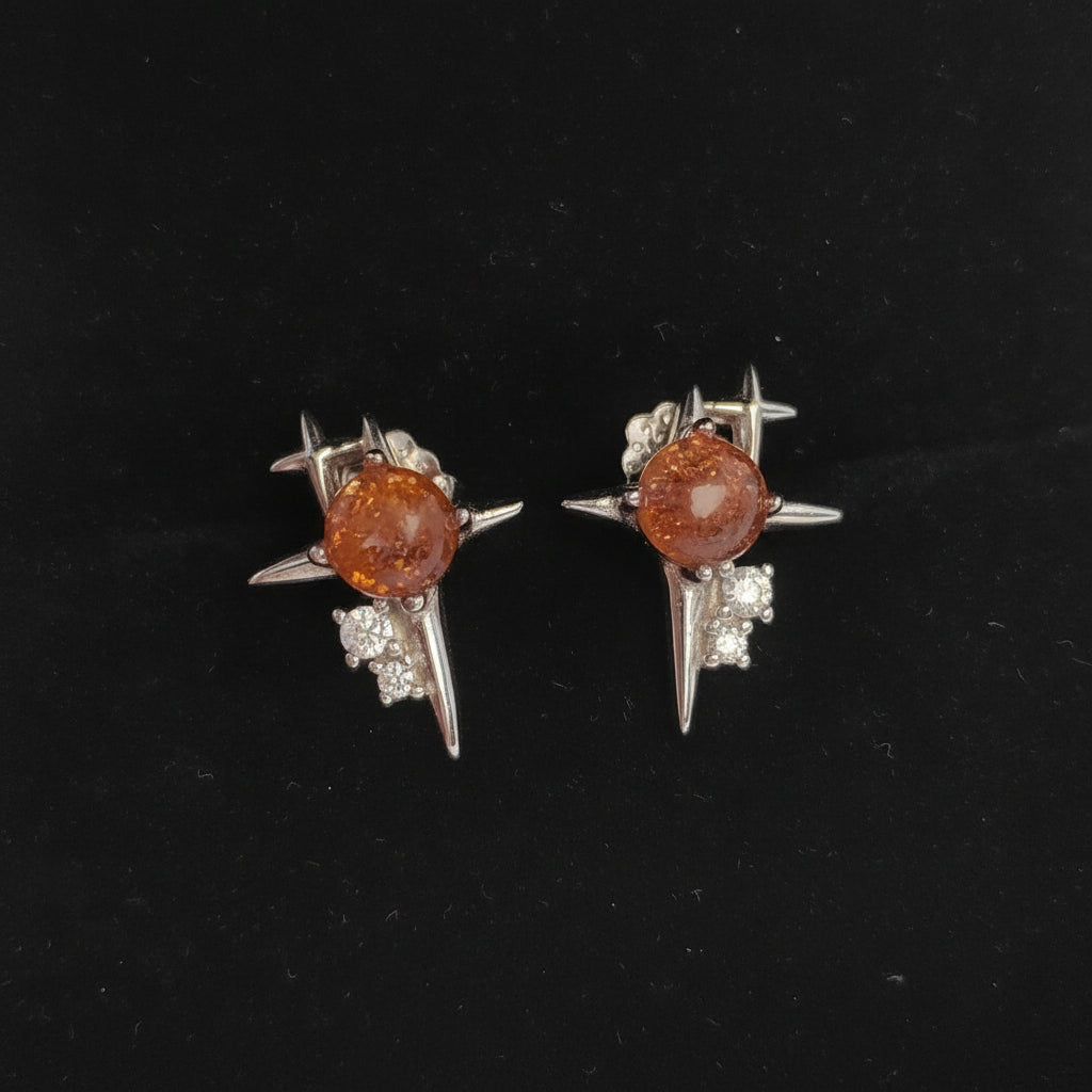 Pair of earrings with brown gemstones and silver star-like designs on a black background