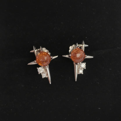 Pair of earrings with brown gemstones and silver star-like designs on a black background