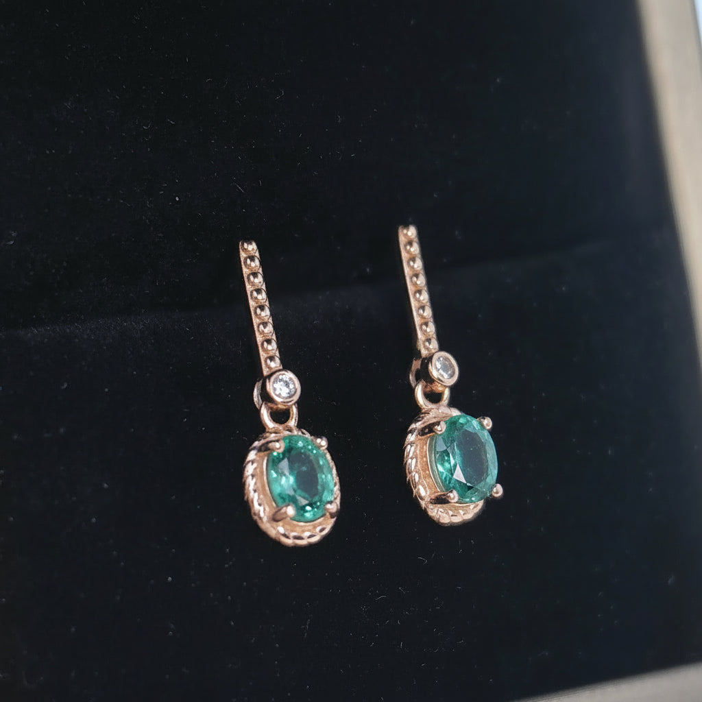 Pair of earrings with green gemstones on a black background