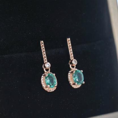 Pair of earrings with green gemstones on a black background