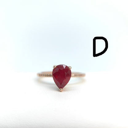 Ring with a pear-shaped red gemstone on a white background
