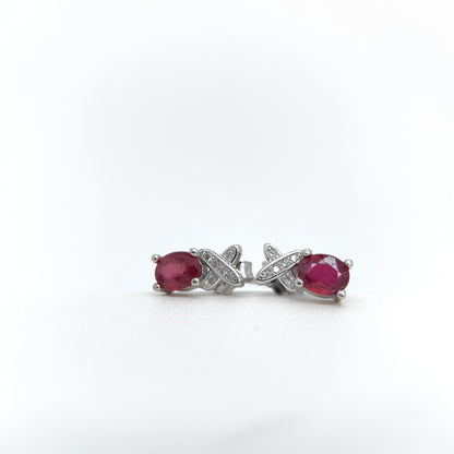 Pair of earrings with red gemstones and silver X-shaped designs on a white background