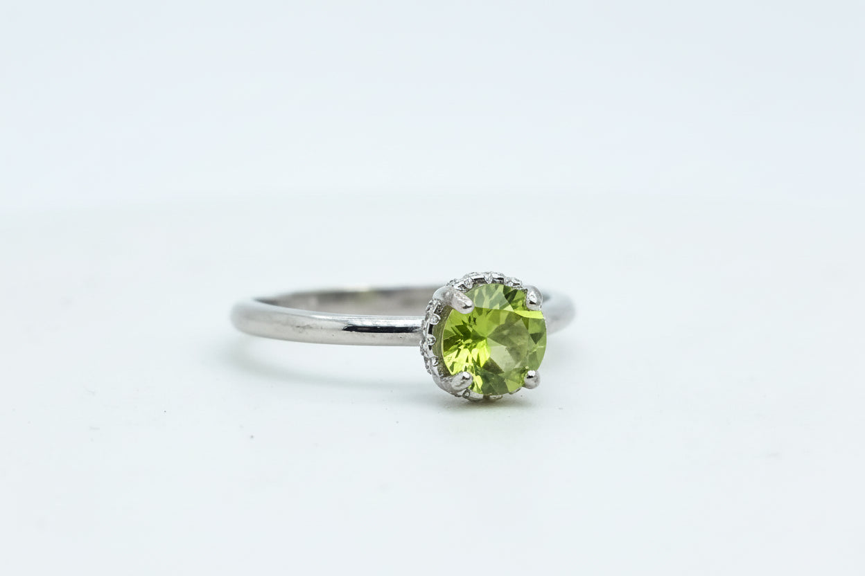 Silver ring with a green gemstone on a light blue background