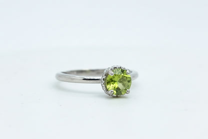 Silver ring with a green gemstone on a light blue background