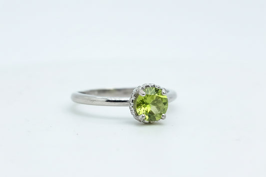 Silver ring with a green gemstone on a light blue background