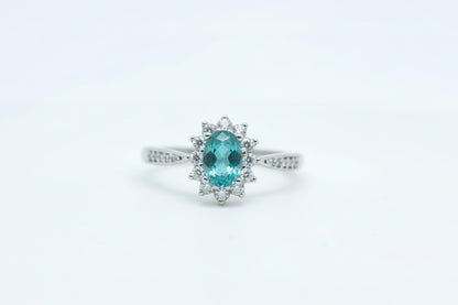 Gold ring with a green gemstone on a light gray background