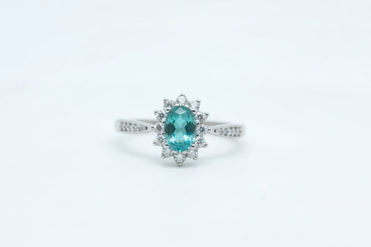 Gold ring with a green gemstone on a light gray background